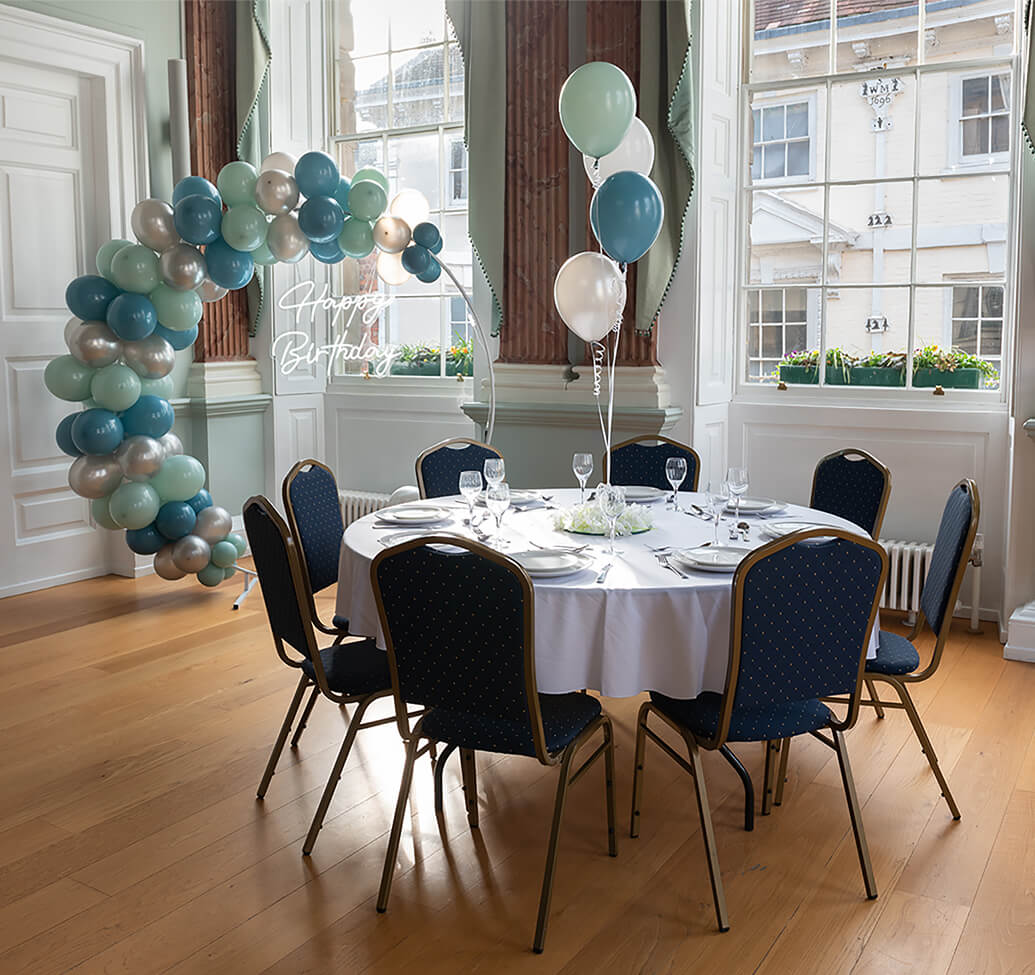 A table decorated with blue and white balloons with a matching balloon circle stand