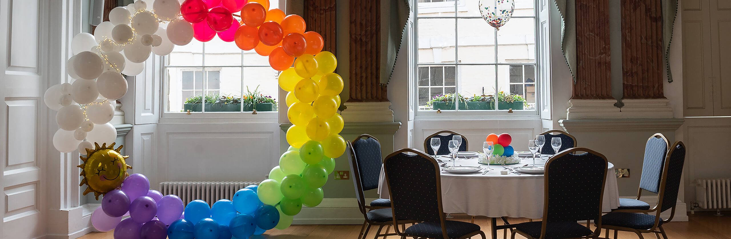A rainbow balloon circle next to a decorated table
